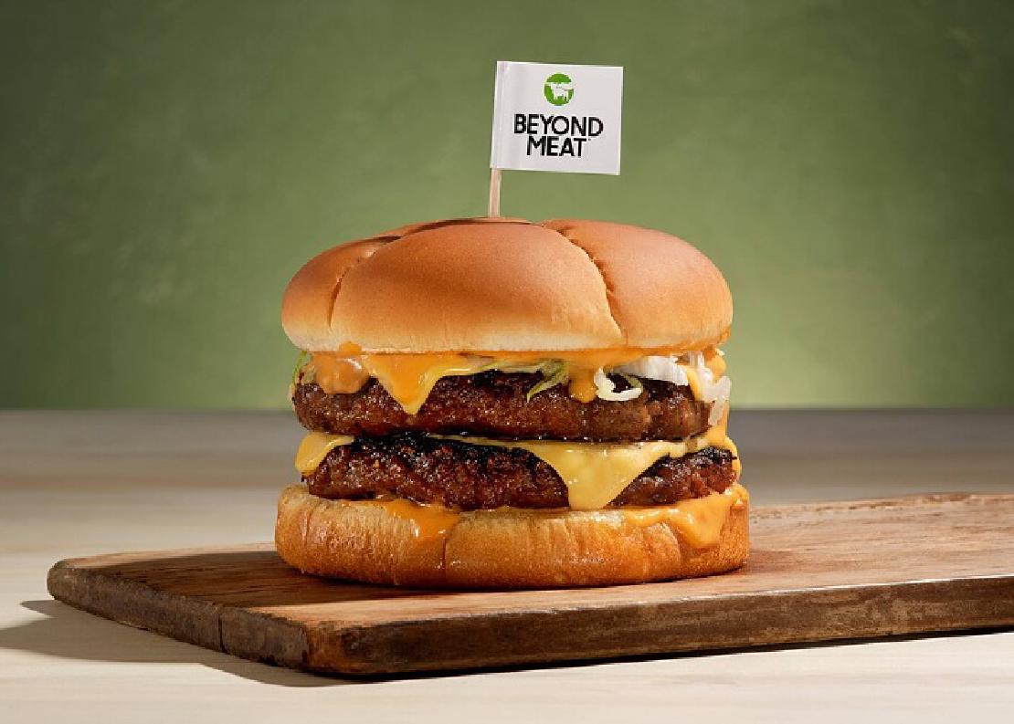 Two Beyond Burger patties on a bun with cheese topped with a little Beyond Meat flag.