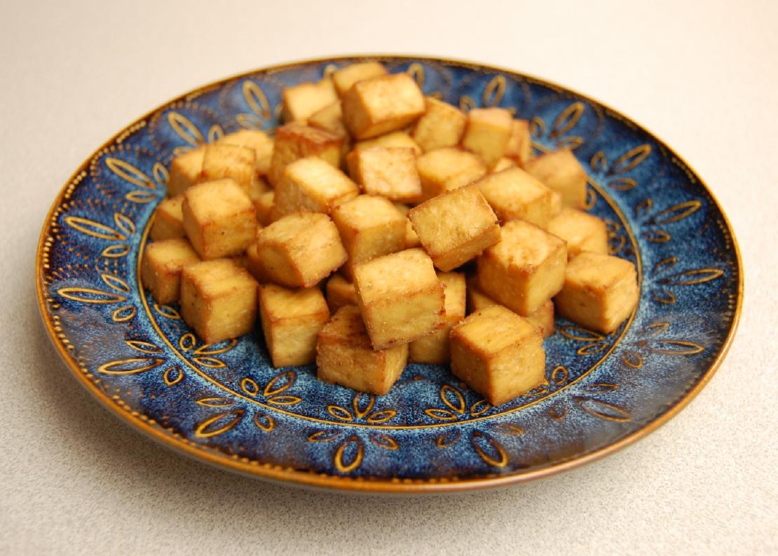 Baked tofu on a blue ceramic plate.