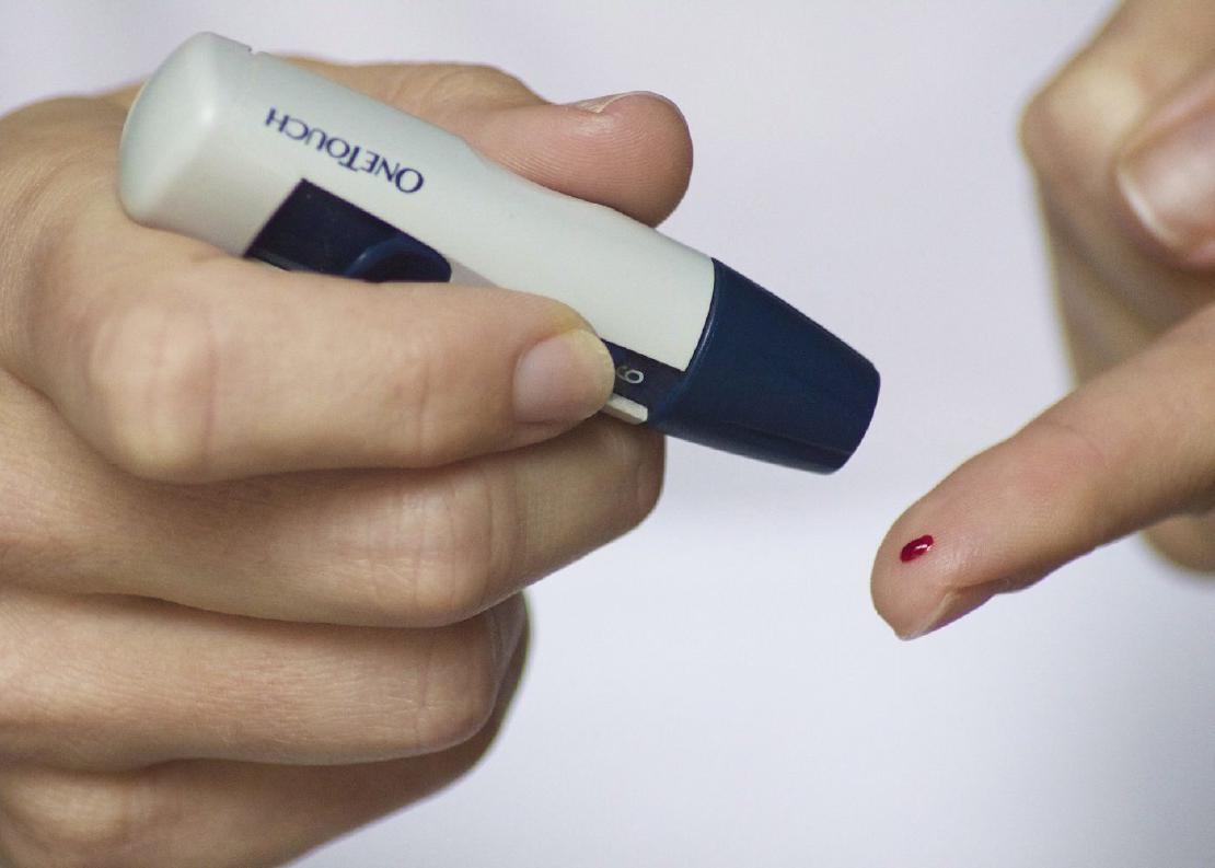A picture of a woman puncturing her finger for a blood sugar levels test.