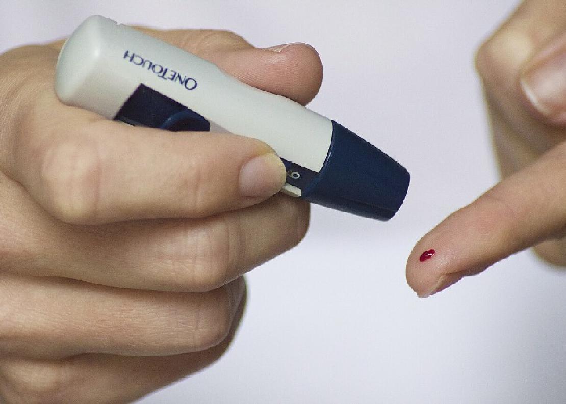 A picture of a woman puncturing her finger for a blood sugar levels test.