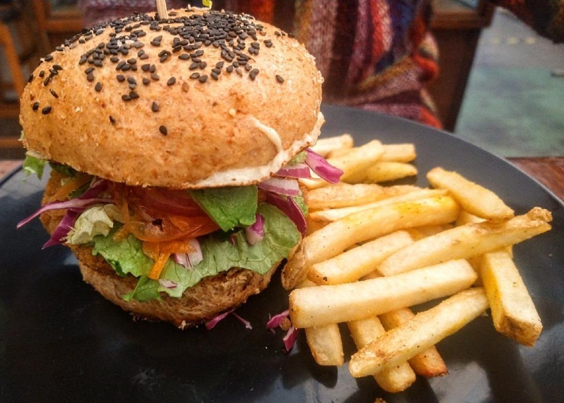 A vegan burger with all the fixings on a plate with French fries.